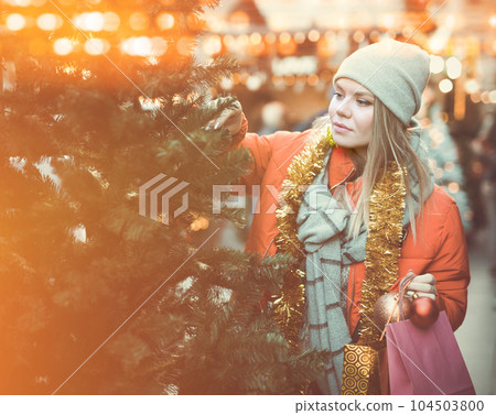 Young woman selecting Christmas tree Young woman selecting Christmas tree 104503800