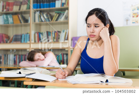 Young girl is thinking about difficult task at the desk Young girl is thinking about difficult task at the desk 104503802