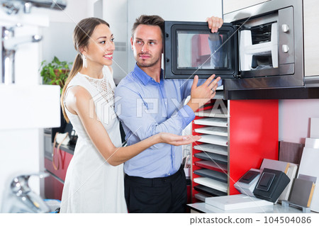 Adult husband and wife are choosing new microwave 104504086
