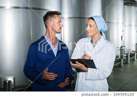 Employees standing with notes in fermentation section 104504120