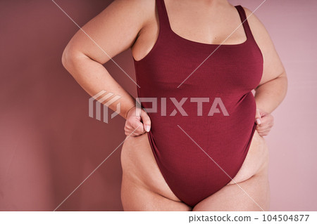 Cropped view of body positive woman posing against pink studio background 104504877