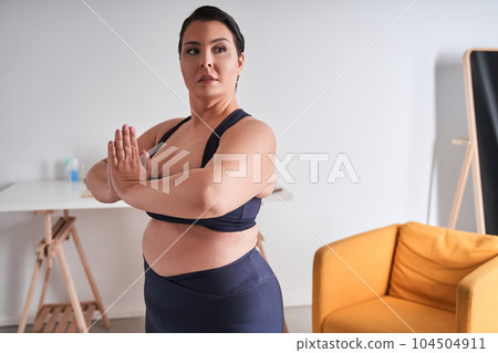Body positive woman holding hands in prayer gesture and looking away Body positive woman holding hands in prayer gesture and looking away 104504911