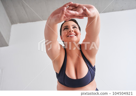 Full figured woman doing morning exercises at home 104504921