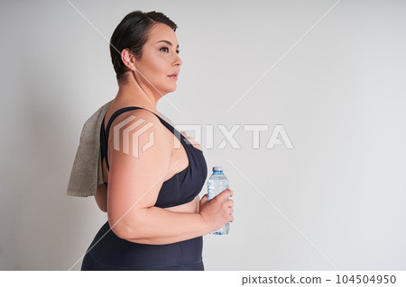Portrait of happy plus size woman holding water bottle 104504950