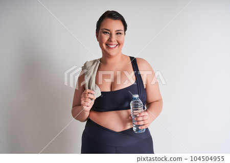 Portrait of happy plus size woman holding water bottle 104504955