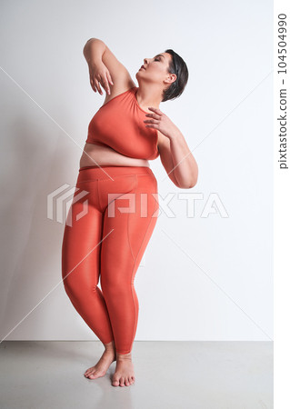 Vertical view of the plus size woman posing alone at studio 104504990