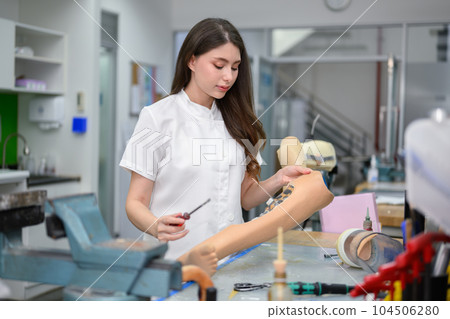 Technician holding prosthetic leg checking and working in laboratory Technician holding prosthetic leg checking and working in laboratory 104506280