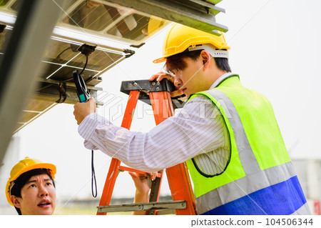 Maintenance engineer checking solar panels on solar cell farm 104506344