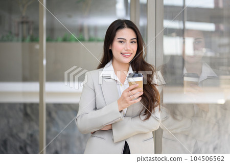 Confident businesswoman with cup of coffee at office 104506562