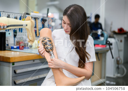 Technician holding prosthetic leg checking and working in laboratory 104506758
