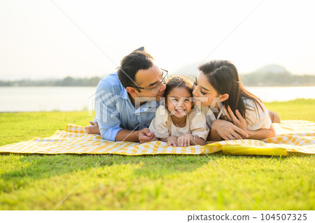 Happy family relaxing and resting in park together on weekend 104507325