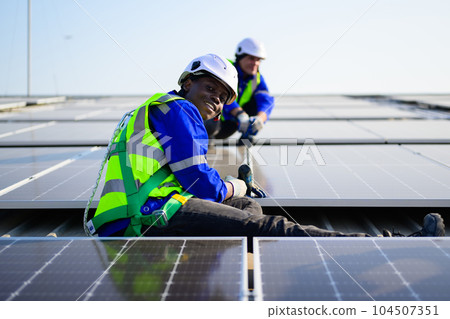 Professional technicians installing solar panels on rooftop of plant Professional technicians installing solar panels on rooftop of plant 104507351