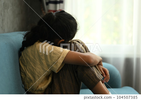 Lonely sad girl student crying and hug her knees sitting in corner Lonely sad girl student crying and hug her knees sitting in corner 104507385