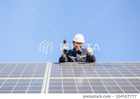 Technician worker installing solar panels at solar cell farm 104507777