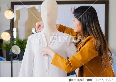 Female fashion designer woman working on her designs in workshop studio, Female business owner with clothes, Tailoring business owner, Clothing store owner, Design fashion clothes by designer 104507998
