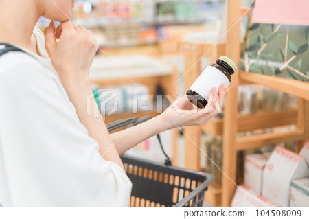 A woman shopping at a pharmacy, drug store, or convenience store A woman shopping at a pharmacy, drug store, or convenience store 104508009