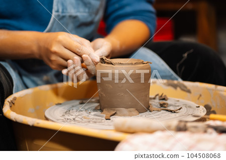 Close up on skillful hands sculpting pottery jar on potter wheel Close up on skillful hands sculpting pottery jar on potter wheel 104508068