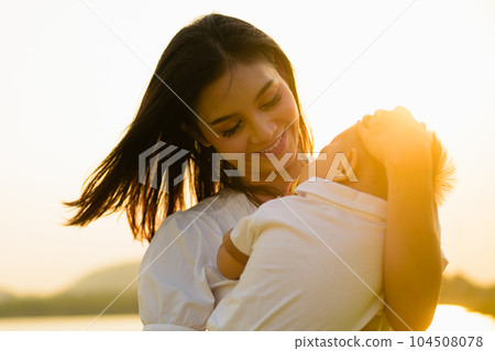 Loving mother holding and carrying her newborn baby at public park 104508078