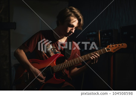 Male Caucasian teenager playing guitar in garage activity music. Generative AI AIG23. Male Caucasian teenager playing guitar in garage activity music. Generative AI AIG23. 104508598