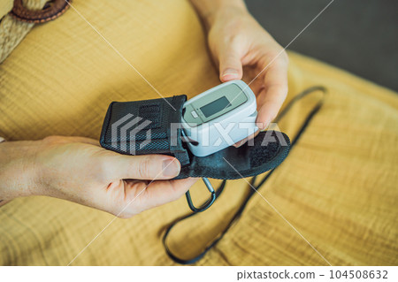 Pregnant woman with pulse oximeter on finger. Doctor measuring oxygen saturation level while visiting expectant mother with coronavirus disease at home, cropped. Pregnancy and covid-19 concept Pregnant woman with pulse oximeter on finger. Doctor measuring oxygen saturation level while visiting expectant mother with coronavirus disease at home, cropped. Pregnancy and covid-19 concept 104508632