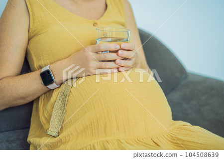 Pregnant woman drinking water. Aerial close up view Pregnant woman drinking water. Aerial close up view 104508639