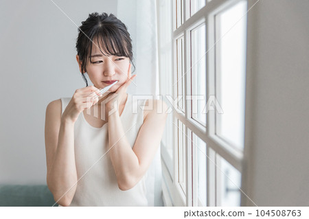 An Asian woman who has a painful tooth decay and holds her cheek An Asian woman who has a painful tooth decay and holds her cheek 104508763