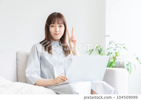 A woman watching a laptop computer in the room 104509099