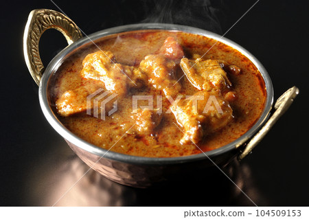 Spicy hot Indian curry with chicken shot on a black background Spicy hot Indian curry with chicken shot on a black background 104509153