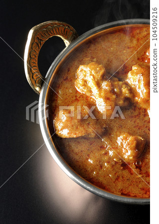 Bird's-eye view of spicy hot Indian curry with chicken on a black background Bird's-eye view of spicy hot Indian curry with chicken on a black background 104509216