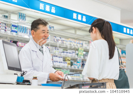 A woman and a pharmacist who consult about medicines and prescriptions at a pharmacy / drug store A woman and a pharmacist who consult about medicines and prescriptions at a pharmacy / drug store 104510945