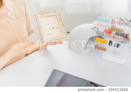 美甲師和亞洲女性在美甲沙龍展示樣品並討論可選設計 104511608