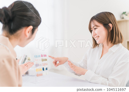 美甲師在美甲沙龍向一位女士解釋看指甲尖並選擇設計 104511697
