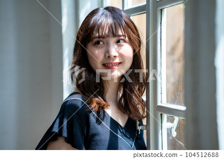 Feminine woman standing by the window Feminine woman standing by the window 104512688