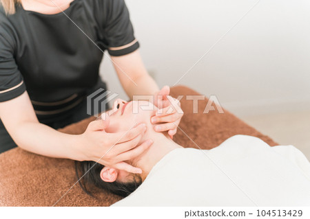 A therapist, esthetician, chiropractor and a woman who perform neck lymphatic massage and small face correction at a chiropractor 104513429