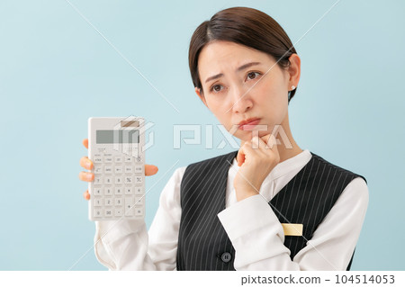 A woman in a uniform who is troubled with a calculator 104514053