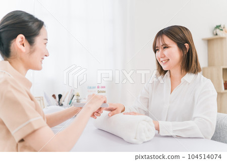 Manicurist sanding at nail salon and Japanese woman receiving treatment 104514074