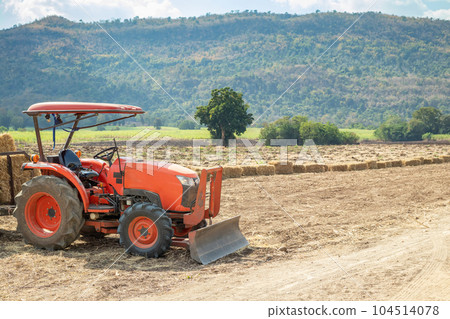 tractor in agriculture field with mountain and blue sky 104514078