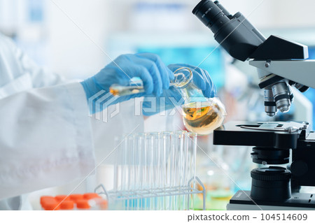 A researcher in a white coat doing research and development using a test tube A researcher in a white coat doing research and development using a test tube 104514609
