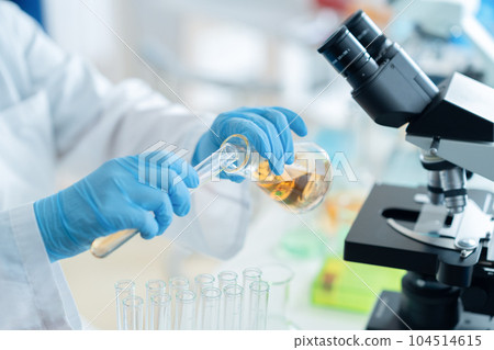 A researcher in a white coat doing research and development using a test tube A researcher in a white coat doing research and development using a test tube 104514615