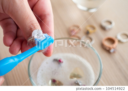 Jeweller hand cleaning and polishing vintage jewelry diamond ring closeup 104514922