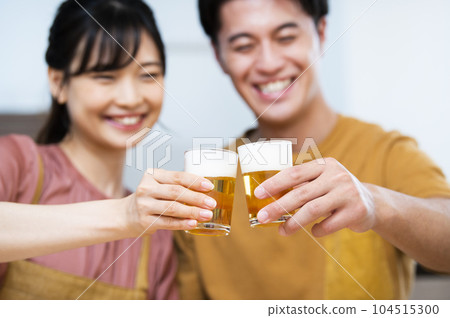 A young couple toasting with beer Focus on hand A young couple toasting with beer Focus on hand 104515300