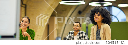 Group of young happy multiracial people sitting at desks in the modern office and listening to coach or speaker during corporate team building training or business seminar Group of young happy multiracial people sitting at desks in the modern office and listening to coach or speaker during corporate team building training or business seminar 104515481