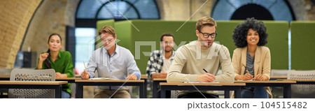 Corporate training. Group of multiracial people sitting in the modern office and listening to coach or speaker during business seminar Corporate training. Group of multiracial people sitting in the modern office and listening to coach or speaker during business seminar 104515482