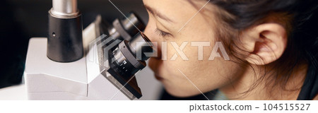 Asian lady doctor looks into contemporary microscope researching sample on slide in hospital Asian lady doctor looks into contemporary microscope researching sample on slide in hospital 104515527