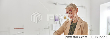 Mature woman designer draws pattern on color fabric at large cut 104515545