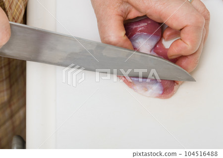 [Housewife preparing yakitori gizzards with a knife] 104516488