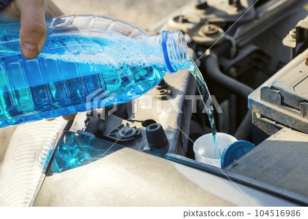 Filling the windshield washer fluid on a car. Filling the windshield washer fluid on a car. 104516986