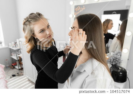 The process of eyebrow correction in the beauty salon. Master carefully applies each brush with great attention, creating individual design that gives a woman's face a special appeal in beauty salon The process of eyebrow correction in the beauty salon. Master carefully applies each brush with great attention, creating individual design that gives a woman's face a special appeal in beauty salon 104517074