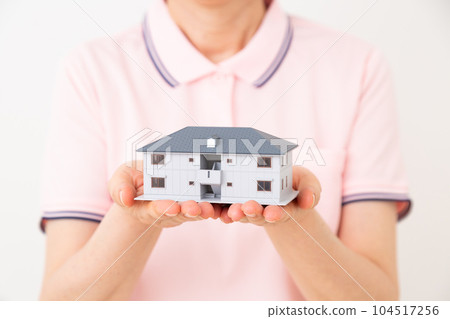一位身穿馬球衫的中年護理人員拿著療養院模型 104517256