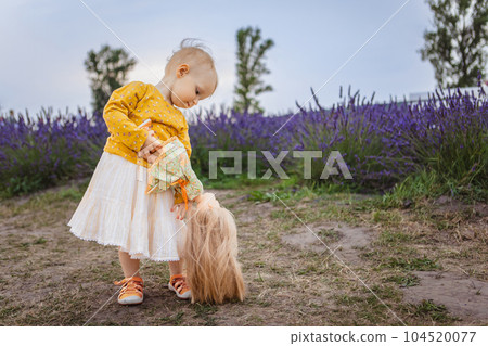 little girl holding a doll on the background of a lavender field 104520077
